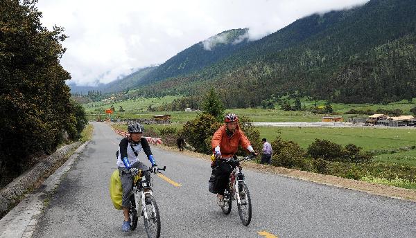 Two tourists ride on a road in the eastern part of southwest China's Tibet Autonomous Region, July 3, 2011. 