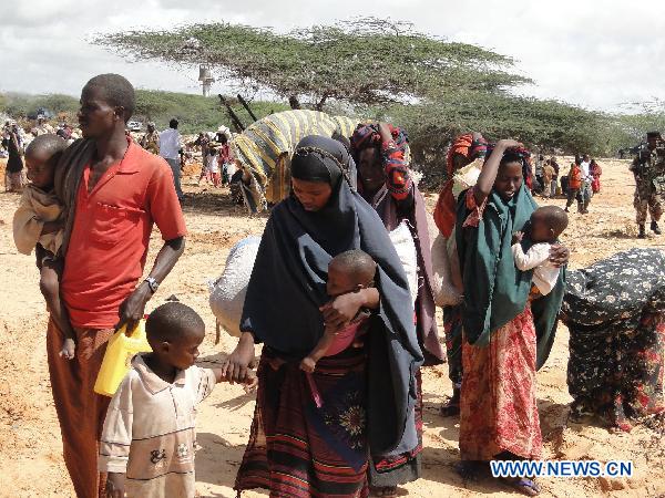 People leave homes for a new camp due to drought in the southwestern outskirts of Mogadishu, capital of Somalia, July 12, 2011. Hundreds of people arrived in government-controlled Mogadishu each day to seek food and shelter. [Faisal Isse/Xinhua]