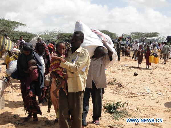 People leave homes for a new camp due to drought in the southwestern outskirts of Mogadishu, capital of Somalia, July 12, 2011. Hundreds of people arrived in government-controlled Mogadishu each day to seek food and shelter. [Faisal Isse/Xinhua] 
