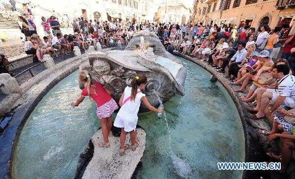 Tourists cool off around the famous Fountain of the Old Boat in downtown Rome, capital of Italy, July 12, 2011. This year&apos;s first heatwave hit Italy recently, which stretched 13 cities including Rome to red alerts on Tuesday. [Xinhua] 
