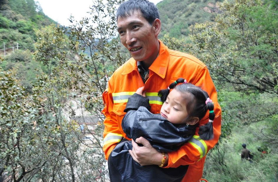 A rescuer holds a child at the landslide site in Yajiang County of Garze Tibetan Autonomous Prefecture in southwest China's Sichuan Province, July 13, 2011. A rain-triggered landslide blocked Yajiang section of National Highway 318 and stranded four people Wednesday morning, who were rescued around noon. No casualties had been reported. 