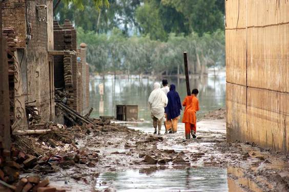 Victims of last year’s floods walk the water-filled streets of the city of Nowshera. [United Nations] 