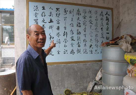 Niu Yinlu shows his calligraphy work, displayed at home in Hantai town, Xinle city, North China's Hebei province, July 14, 2011.