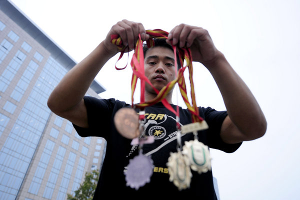 Zhang shows off some medals he won years ago, some of which he sold for cash. 