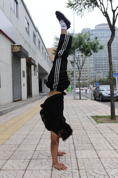 Zhang Shangwu, 27, a former gymnastics champion, performs handstands on Beijing's Wangfujing commercial street on July 14, 2011. Since leaving the sport, he has had a hard time and is now doing street performance to make a living.