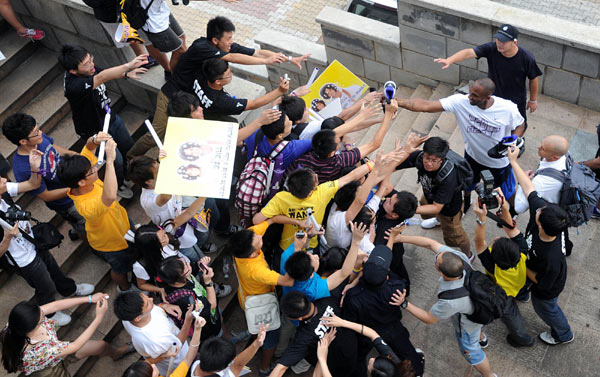 NBA basketball player Kobe Bryant (2nd R) of the Los Angeles Lakers gives his shoes to fans upon his arrival at a stadium during his 2011 China Tour in Changsha, Central China's Hunan province, July 16, 2011. 