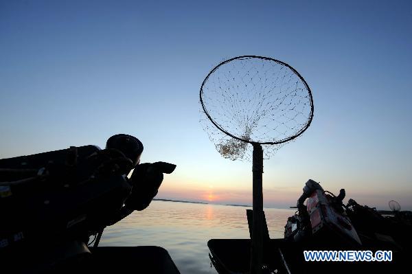 Dawn breaks as fishermen trawl in the waters of the Heixiazi Island near Fuyuan County, northeast China's Heilongjiang Province, July 18, 2011. [Xinhua/Wang Jianwei]