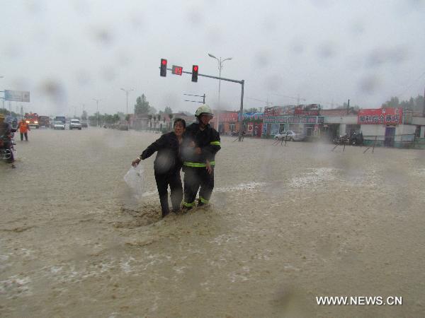 A firefighter helps to transfer a trapped resident on the waterlogged road at Daban town in Chifeng City, north China&apos;s Inner Mongolia Autonomous Region, July 18, 2011. Heavy rain hit the town on Monday, causing waterlog and interfering local traffic. No casualties had been reported by press time. [Xinhua] 