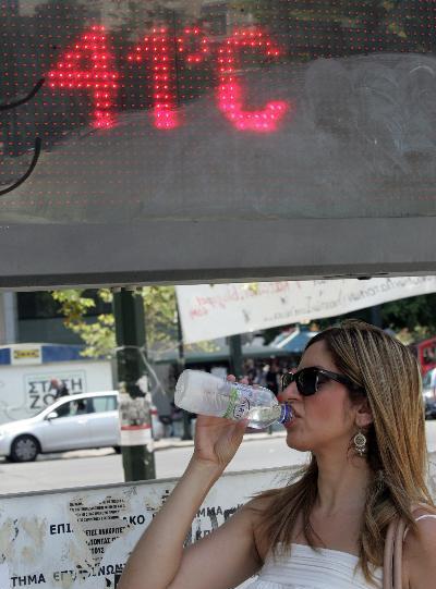 A girl drinks water to tackle the heat wave as a thermometer above shows 41 degrees Celsius in central Athens, capital of Greece, on July 19, 2011. Greece is hit by a heat wave over the past few days. [Xinhua]