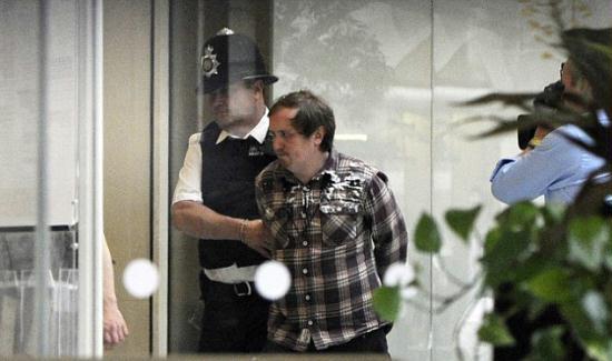 Marbles is escorted out of Parliament by a police officer after his attack on Rupert Murdoch