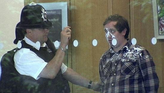 A policeman photographs Jonnie Marbles outside the Committee room shortly after the incident