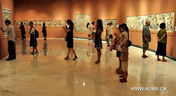 Visitors look at the exhibited Dunhuang art works in Shenzhen of south China's Guangdong Province, July 21, 2011. An exhibition of the Dunhuang art works was opened in Guanshanyue art gallery here on Wednesday, exhibiting multiple cultural relics, including paintings and scriptures. 