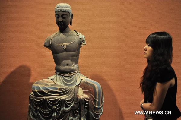 A visitor looks at the exhibited Dunhuang art work in Shenzhen of south China's Guangdong Province, July 21, 2011. An exhibition of the Dunhuang art works was opened in Guanshanyue art gallery here on Wednesday, exhibiting multiple cultural relics, including paintings and scriptures.