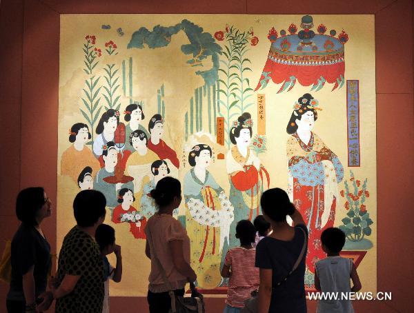 Visitors look at the exhibited Dunhuang art work in Shenzhen of south China's Guangdong Province, July 21, 2011. An exhibition of the Dunhuang art works was opened in Guanshanyue art gallery here on Wednesday, exhibiting multiple cultural relics, including paintings and scriptures.