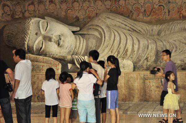 Visitors look at the exhibited Dunhuang art work in Shenzhen of south China's Guangdong Province, July 21, 2011. An exhibition of the Dunhuang art works was opened in Guanshanyue art gallery here on Wednesday, exhibiting multiple cultural relics, including paintings and scriptures.