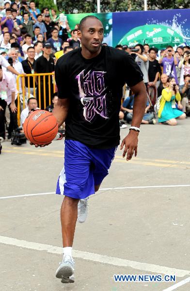 Kobe Bryant demonstrates dribbling skills to young players in east China's Shanghai, July 21, 2011. As part of his Asian tour, NBA star Kobe Bryant met and gave instructions to young Chinese players in the final of a basketball contest Thursday in Shanghai.