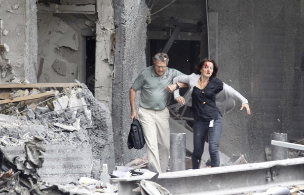 An injured woman is helped by a man at the scene of a powerful explosion that rocked central Oslo July 22, 2011. [Agencies] 