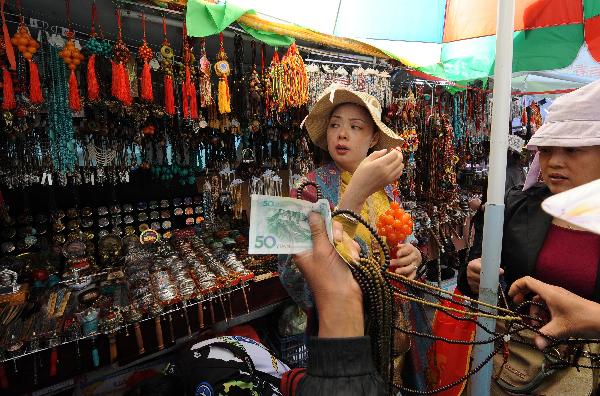 Tourists are seen in a market in Lhasa, capital of southwest China's Tibet Autonomous Region, July 24, 2011. A large number of tourists poured into Tibet during the summer season, as the region is celebrating the 60th anniversary of its peaceful liberation. The region received 2.25 million tourists in the first half of this year, 24.8 percent more than the same period of last year. [Xinhua/Chogo]