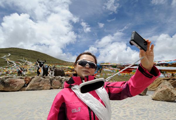 A woman takes photos of herself on the Milha Mountain in Nyingchi of southwest China's Tibet Autonomous Region, July 2, 2011. A large number of tourists poured into Tibet during the summer season, as the region is celebrating the 60th anniversary of its peaceful liberation. The region received 2.25 million tourists in the first half of this year, 24.8 percent more than the same period of last year. (Xinhua/Chogo)