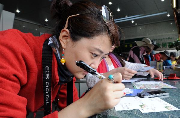 A tourist writes postcards in a postal office in Lhasa, capital of southwest China's Tibet Autonomous Region, July 24, 2011. A large number of tourists poured into Tibet during the summer season, as the region is celebrating the 60th anniversary of its peaceful liberation. The region received 2.25 million tourists in the first half of this year, 24.8 percent more than the same period of last year. (Xinhua/Chogo) 