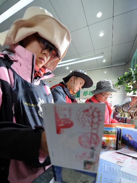 A tourist selects postcards in a postal office in Lhasa, capital of southwest China's Tibet Autonomous Region, July 24, 2011. A large number of tourists poured into Tibet during the summer season, as the region is celebrating the 60th anniversary of its peaceful liberation. The region received 2.25 million tourists in the first half of this year, 24.8 percent more than the same period of last year. (Xinhua/Chogo)