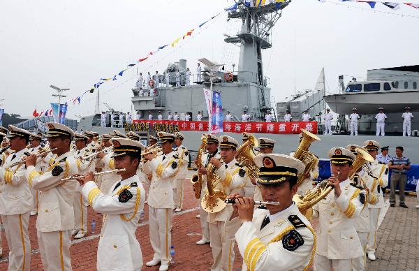 A millitary band performs in front of China's missile frigate 'Wuhu' during the 2011 International Marine Festival in Qingdao, east China's Shandong Province, July 23, 2011. The missile frigate is open for visitors during the festival, which kicked off on Saturday, as an effort to promote national defense education. [Xinhua/Li Ziheng]