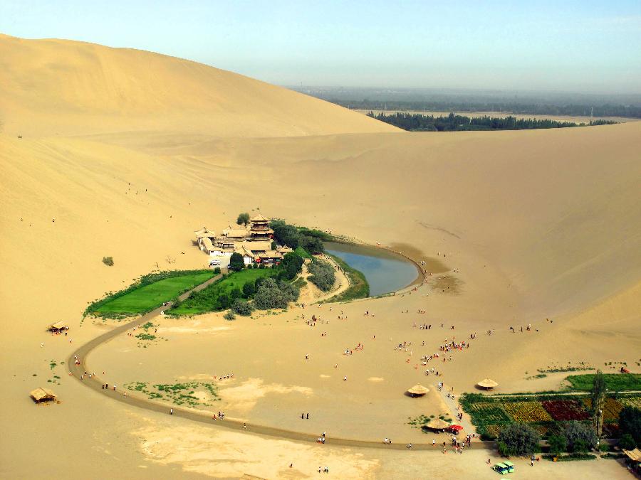 Photo taken on July 25, 2011 shows the rich oasis scenery zone of Yueya Spring (Crescent Spring) and the adjacent Mingsha Mountain Dunes (Singing-Sand Dunes) coexisting in Dunhuang City, northwest China's Gansu Province. 