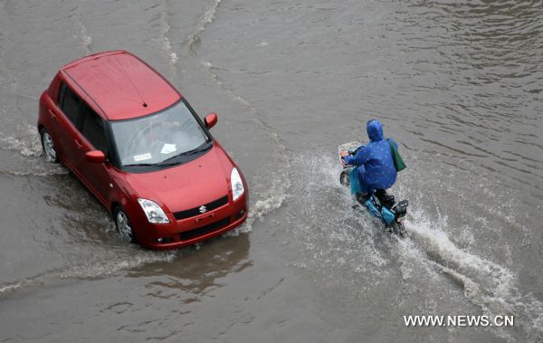 A car moves on a flooded road in Tianjin, north China, July 25, 2011. Following Sunday&apos;s rainstorm, Tianjin received another heavy rainfall on Monday morning. [Xinhua]