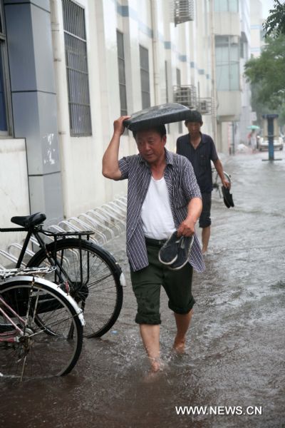 Pedestrians walk on a flooded street in Tianjin, north China, July 25, 2011. Following Sunday&apos;s rainstorm, Tianjin received another heavy rainfall on Monday morning. 