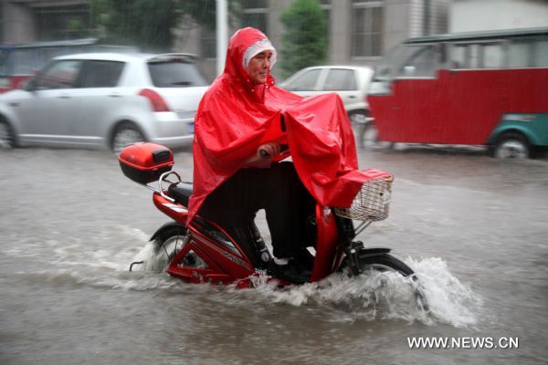 A citizen rides in rain in Tianjin, north China, July 25, 2011. Following Sunday&apos;s rainstorm, Tianjin received another heavy rainfall on Monday morning. 