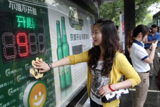 Yu Yingqi, 24, presses the happy face screen to express her good mood at a bus station in Wangfujing street, Beijing, on July 20.