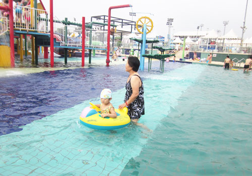 A mother pushes her child in an inner tube in the kiddie pool at Chaoyang Park beach. [Photo:CRIENGLISH.com]