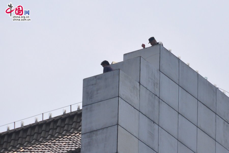 The man (L1) threatens to jump off the roof of Parkson Plaza, at Fuxingmen, central Beijing. [Maverick Chen / China.org.cn]