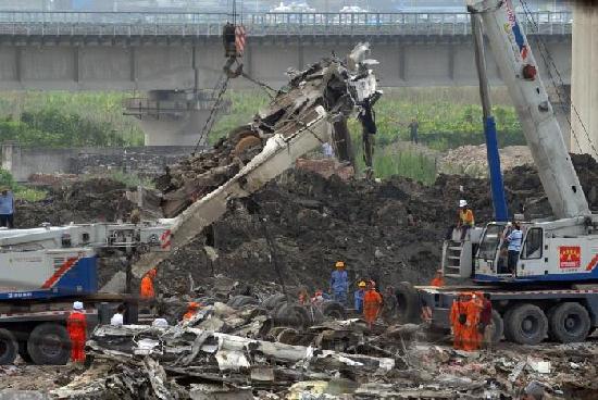 Cranes and excavators are used to carry out cleanup work of two trains at the derail site near the city of Wenzhou in East China's Zhejiang province on early Tuesday morning, 2011.