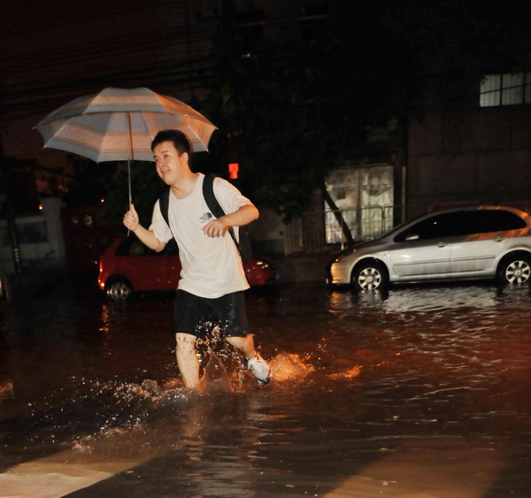 A pedestrian wades through a flooded street after torrential rains in downtown Beijing, July 26, 2011. A large-scale rainstorm hit the city Tuesday night, with an average precipitation of 60 mm in nine hours, the most in 13 years.