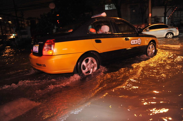 A taxi travels through a flooded street in downtown Beijing, July 26, 2011. [Photo/Xinhua] 