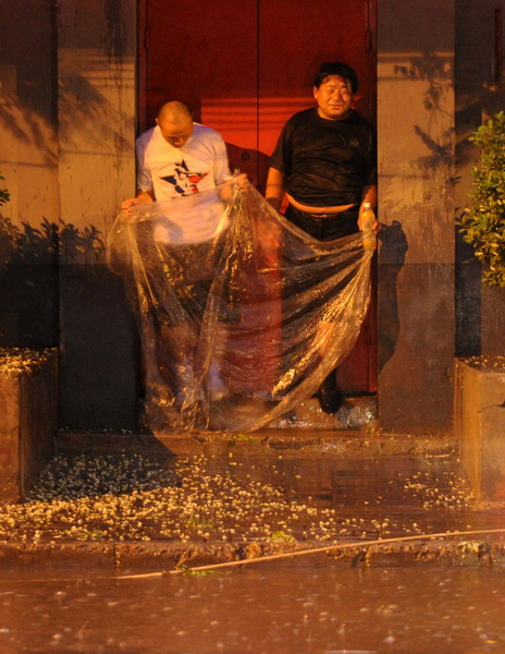 Two pedestrians take shelter from rain Tuesday night in downtown Beijing. [Photo/Xinhua]