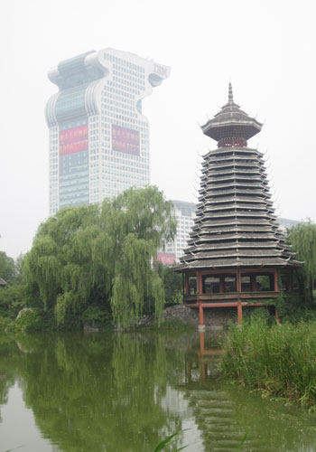 A traditional lakeside pavilion in the China Ethnic Culture Park stands in contrast to the iconic Olympic torch building. [Photo:CRIENGLISH.com]