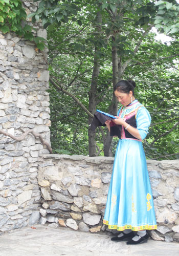 A woman dressed in traditional Qiang costume practices embroidery at the China Ethnic Culture Park. [Photo:CRIENGLISH.com]