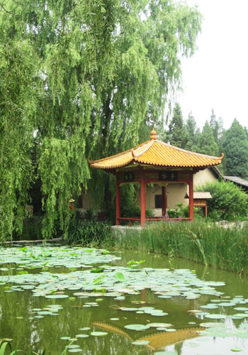 A serene pavilion sits on the banks of a pond near the Manchu village in the China Ethnic Culture Park. [Photo:CRIENGLISH.com]