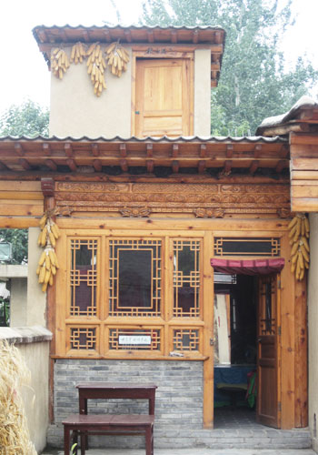 The buildings in the Tujia village in the China Ethnic Culture Park have dried corn hanging on the walls, a common sight in inland China. [Photo:CRIENGLISH.com]