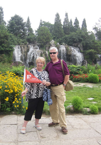 American tourists Steve and Joann Letnaunchyn pose with their CITS tour flag in the China Ethnic Culture Park. [Photo:CRIENGLISH.com]