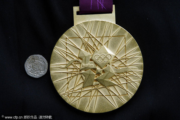 The back of 2012 Olympic Gold medal next to a twenty pence coin during a photocall at the London Organising Committee of the Olympic Games 2012 in Canary Wharf, London.