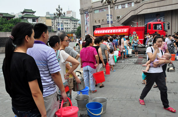 Residents in Mianyang city in Sichuan province stand in line to get water from a fire truck on Wednesday. [Xinhua] 
