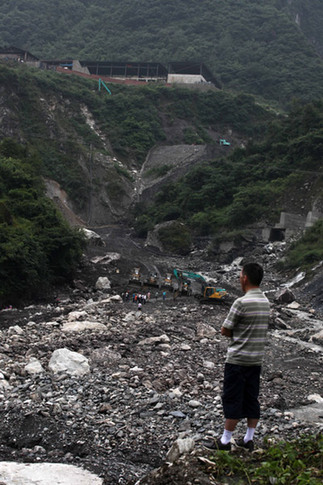 A resident in Songpan county in Mianyang city, Southwest China's Sichuan province, looks on Wednesday at residue that was washed away from a local manganese plant by floodwaters. [China Daily] 