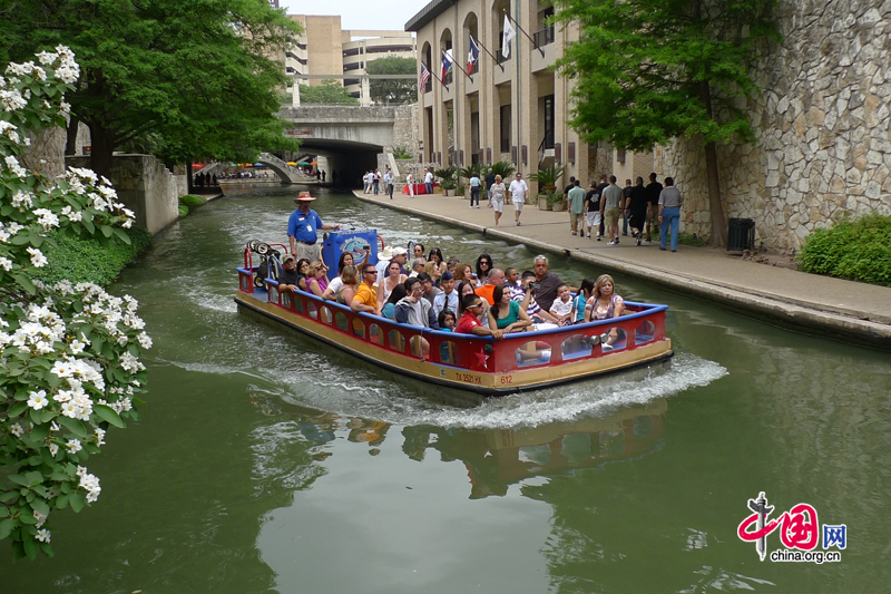 A river taxi guides tourists through the San Antonio River Walk, a network of walkways along the banks of the San Antonio River, extending some 2.5 miles, in Texas, US. Lined by bars, shops and restaurants, the River Walk is an important part of the city's urban fabric and a tourist attraction, attracting several million visitors every year. [Photo by Xu Lin / China.org.cn]