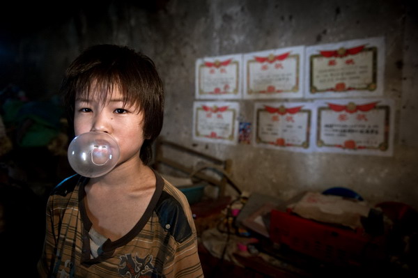 Sun's oldest child, 11 year-old Sun Wanli, eats bubble gum in the house in Woyang county, East China's Anhui province, July 28, 2011. [Photo/Xinhua]