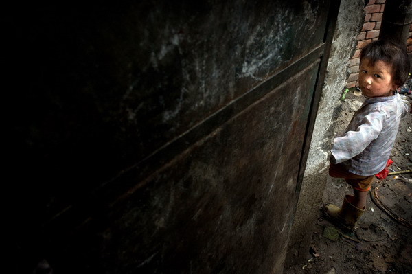 Sun Yuke poses by the family's house in Woyang county, East China's Anhui province, July 27, 2011. [Photo/Xinhua] 