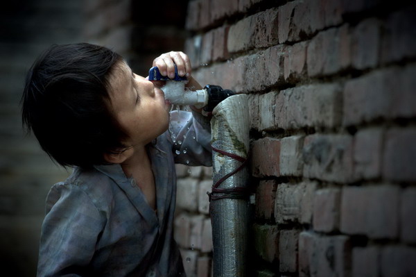 Five-year-old Sun Yuke, the youngest boy, drinks from a running water pipe in Woyang county, East China's Anhui province, July 27, 2011. [Photo/Xinhua] 