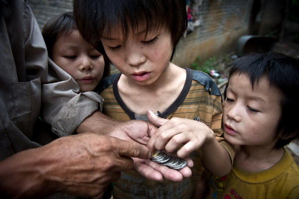 Sun Wanli counts the income his father earned in Woyang county, East China's Anhui province, July 27, 2011. His father earned 9.1 yuan selling salvaged rubbish that day. [Photo/Xinhua]